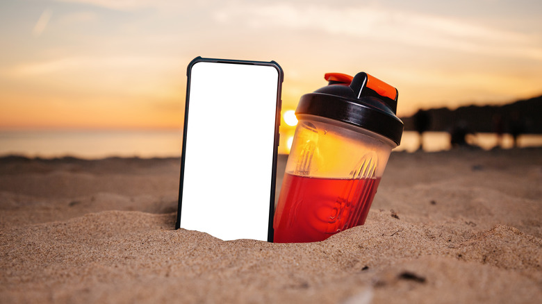 Phone and bottle in sand