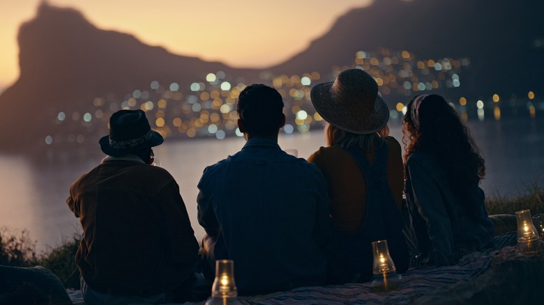 silhouetted people looking at sunset