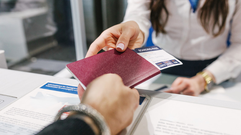 passenger handing a passport and boarding pass to an agent