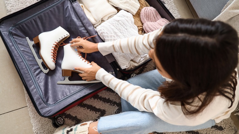 woman packing skates in suitcase