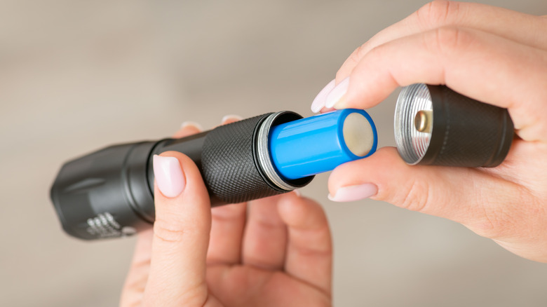 Person removing battery from flashlight