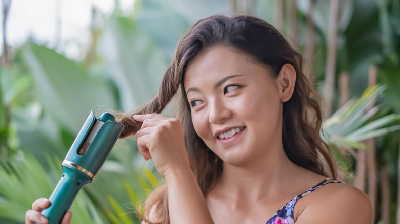 Woman curling her hair on a trip.