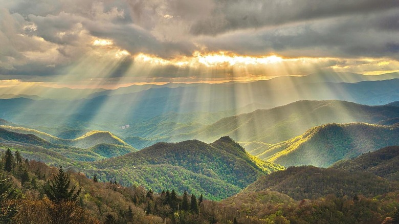 sun shining through clouds mountains