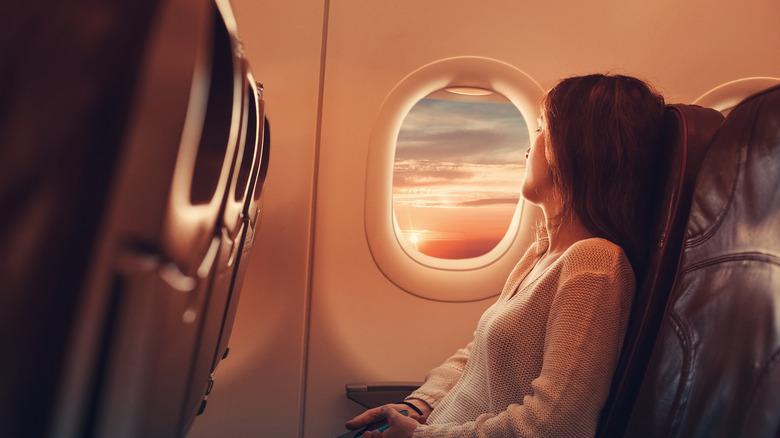 woman looking out airplane window