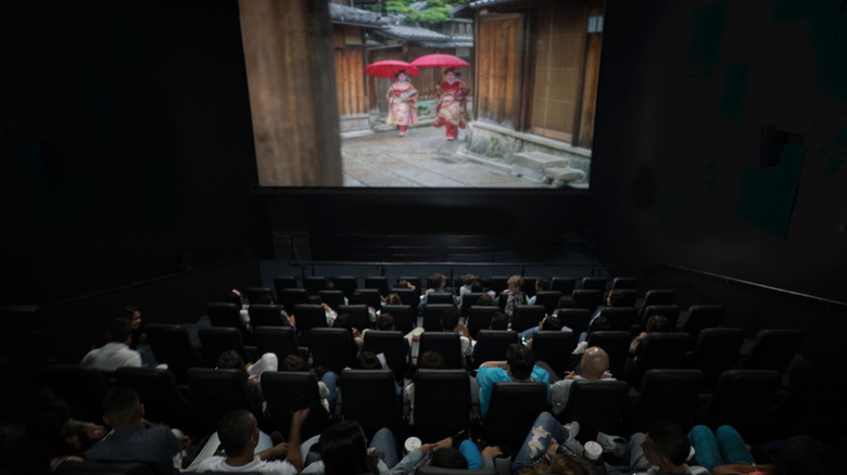 An audience watching a movie inside a dark theater