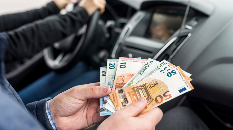Man holding Euros in a taxi