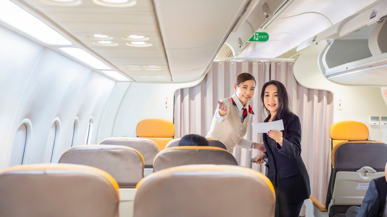 Flight attendant directing passenger