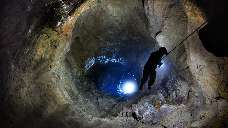 Speleologist abseiling into cave
