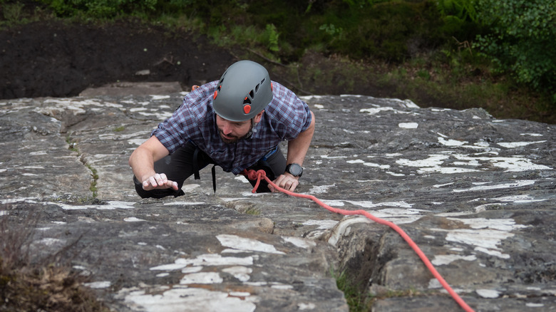 person climbing cliffside rock