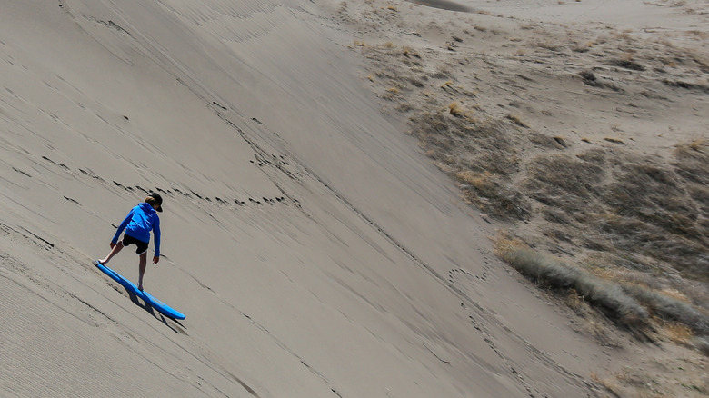 Boy sandboarding on the dunes