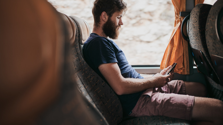 Traveler on bus looking at phone