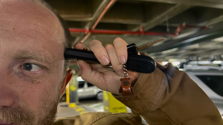 Man holding up car remote to his head