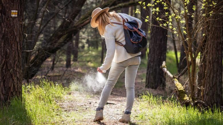Hiker in light clothing spraying repellent