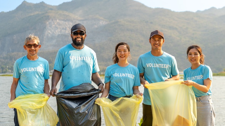 Volunteers smile with trash bags on beach