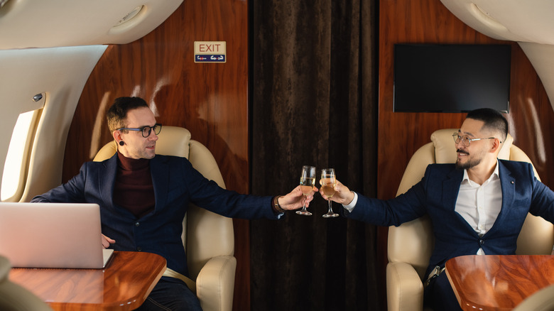 Two passengers in business class clinking champagne glasses