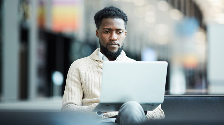 man in airport using laptop