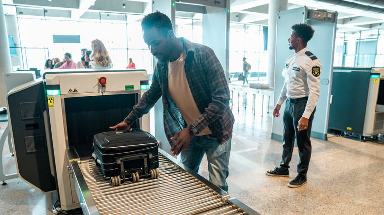 Man retrieving suitcase in security