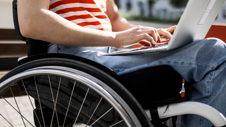 Wheelchair user typing on laptop