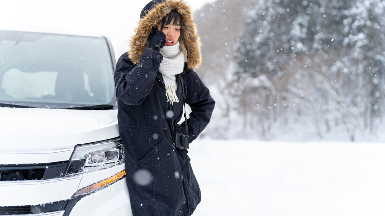 Driver standing by car stuck in snow