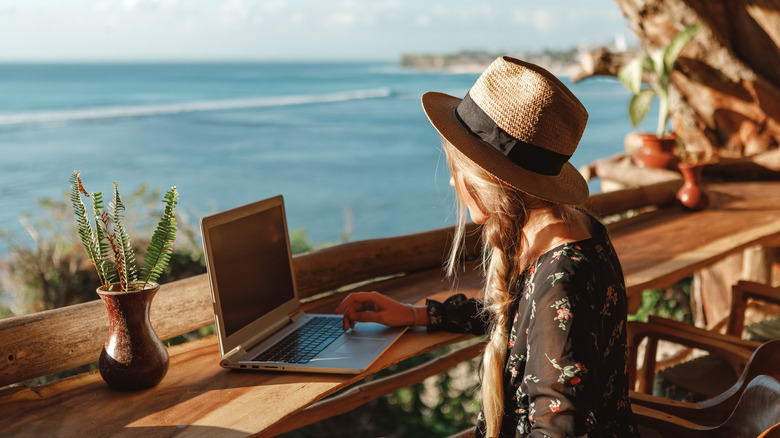 woman checking laptop by sea