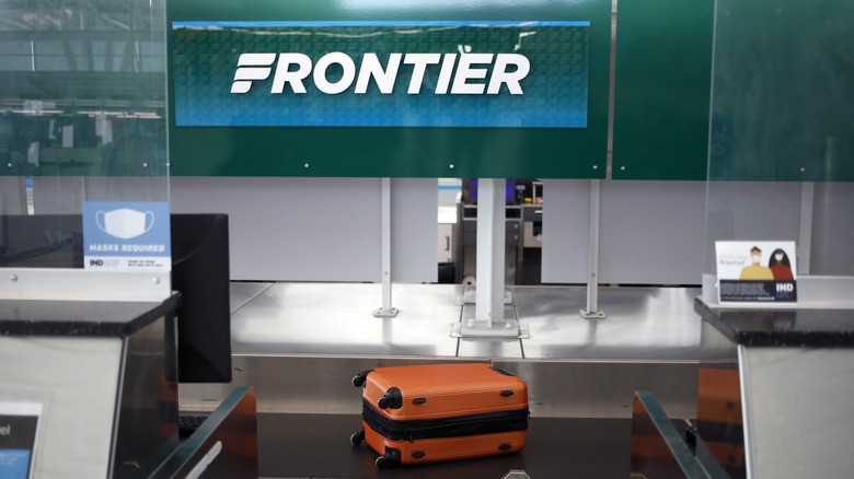 orange suitcase frontier check-in counter