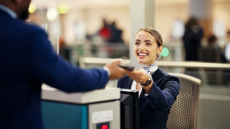 airline employee handing passenger ticket