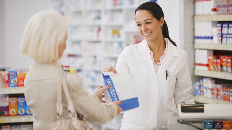 pharmacist handing customer her prescription