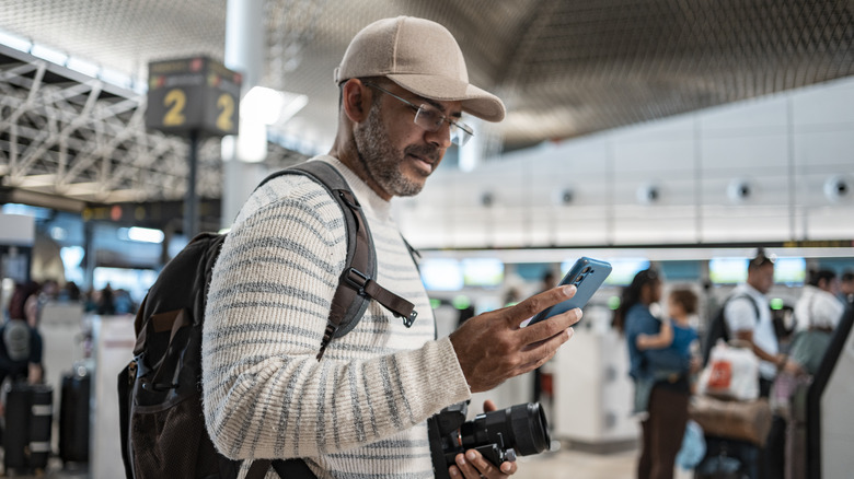 man holding phone at airport