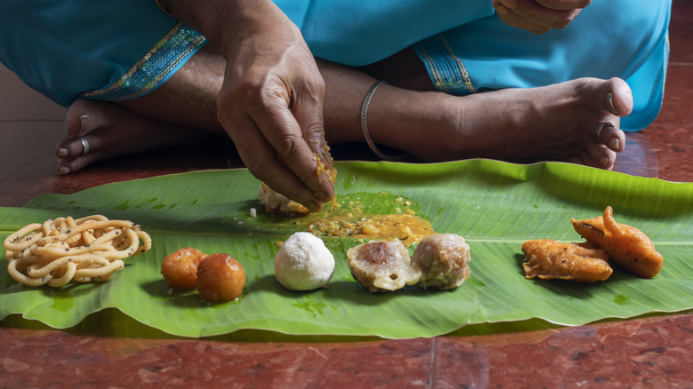 A woman eats food off a banana leaf in India