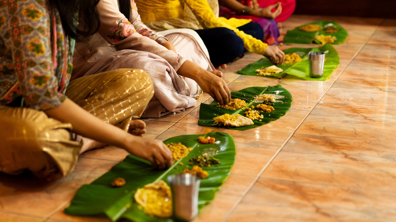 People eat food off banana leaves in India