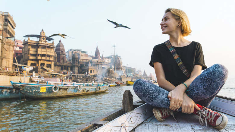 Young woman sits cross legged on a boat in India