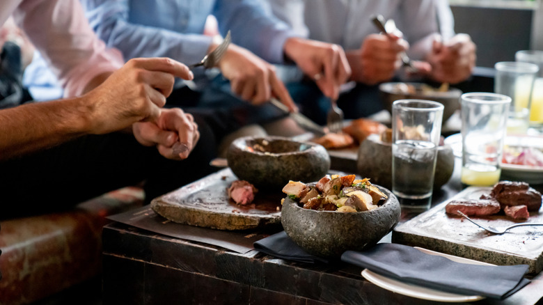 Three people eat a meal with knives and forks