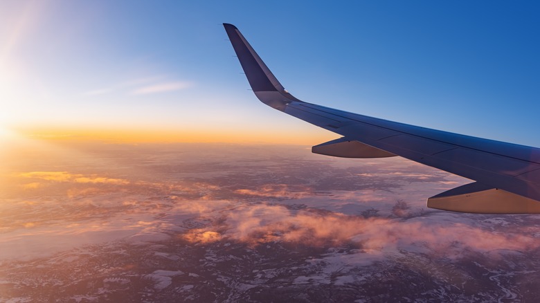 Airplane wing over snowy mountains