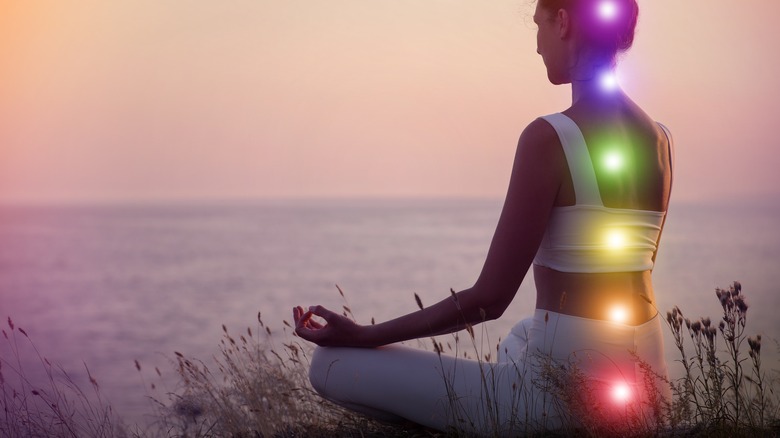 human meditating by the beach chakras aligning