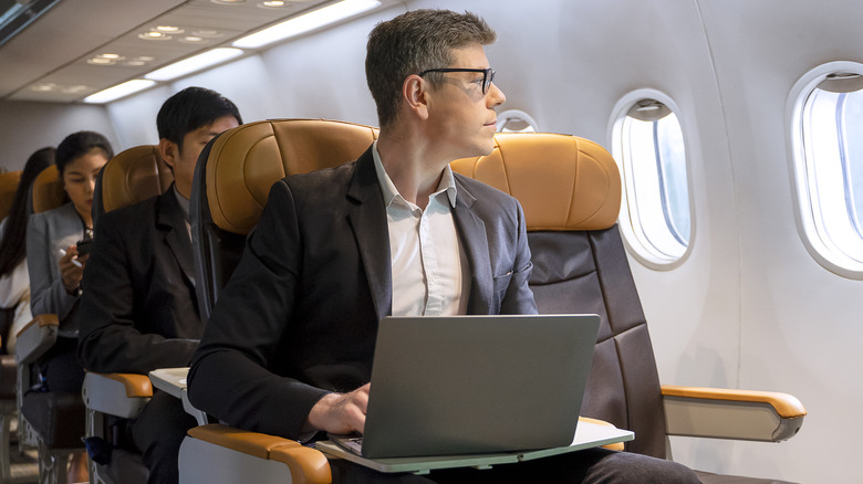 man sitting on airplane with laptop