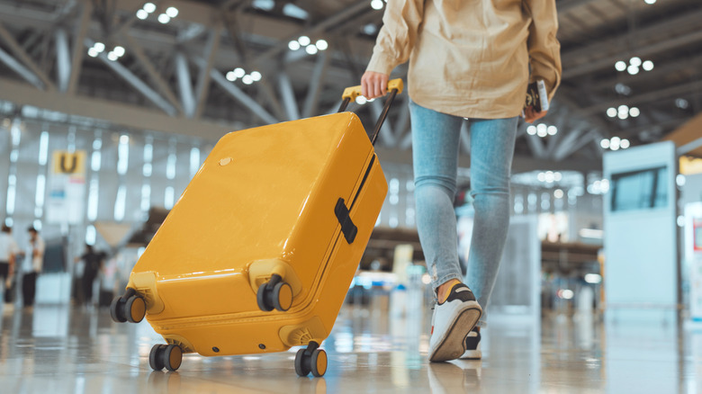 person walking with yellow suitcase in airport