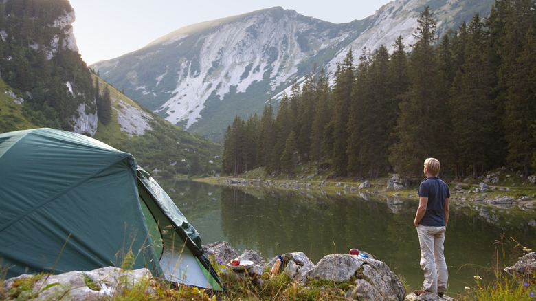 man camping by mountain lake 