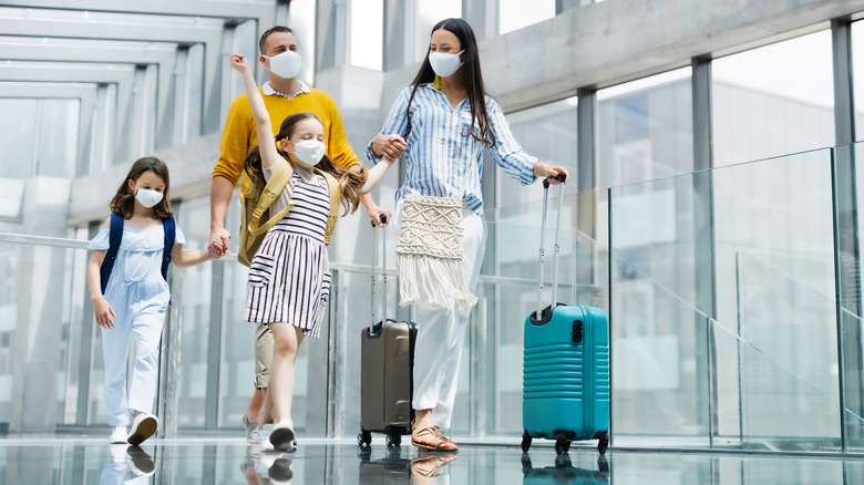 Family with two children going on holiday, wearing face masks at the airport.