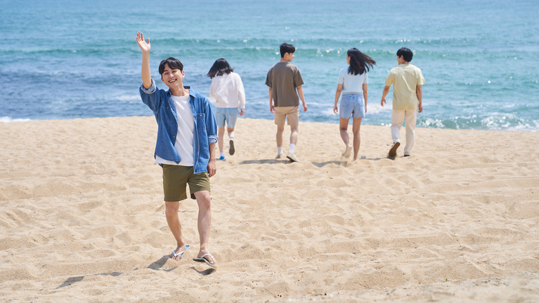 A youth waves from the beach in South Korea