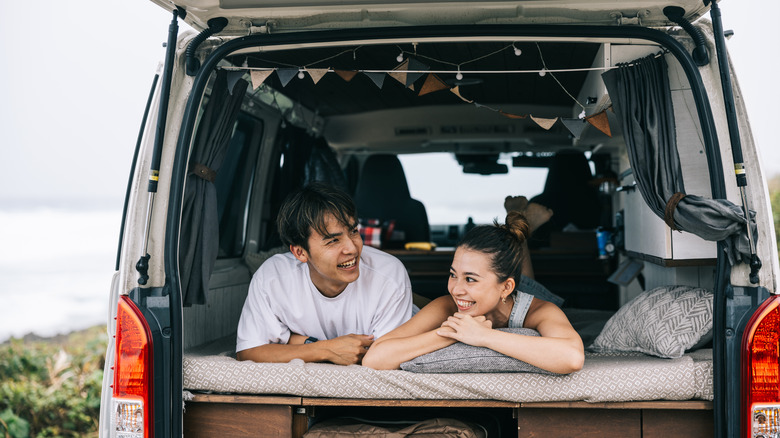 A couple lounges in the back of a camper van in Japan