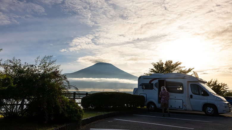 A woman stands next to her camper van in front of Mt. Fuji