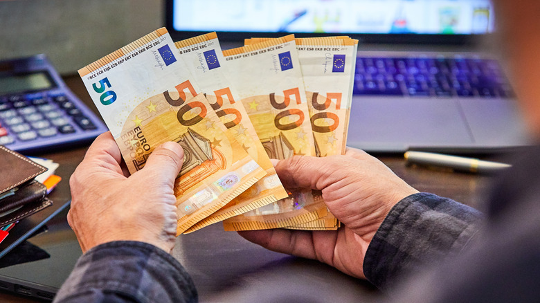 A man counts out 50 Euro notes at a bank