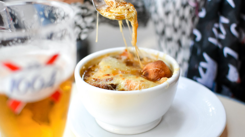 A spoon dipping into a bowl of French onion soup