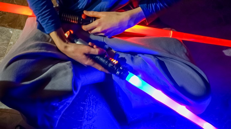 A person holding blue and red lightsabers