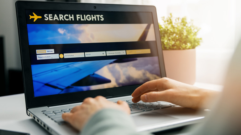 Person searching flights laptop