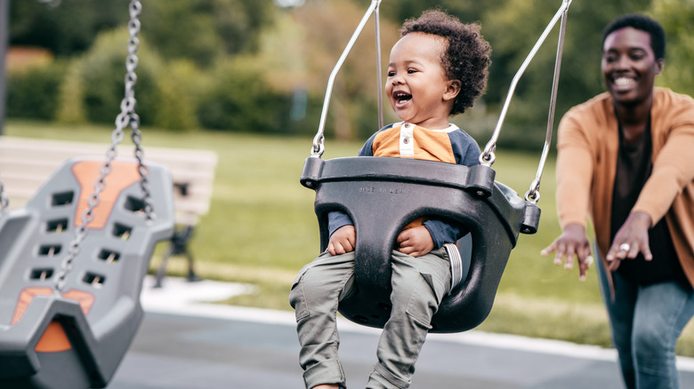 Person pushing baby in swing