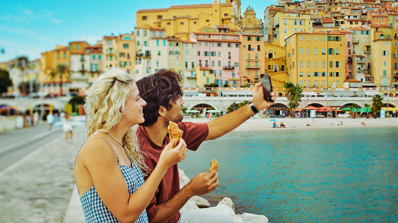 Travel couple posing for a selfie by the beach