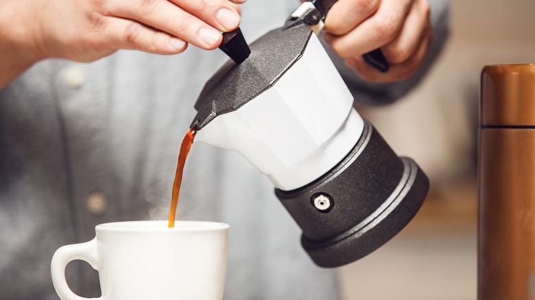 Pouring coffee in a cup from a moka pot