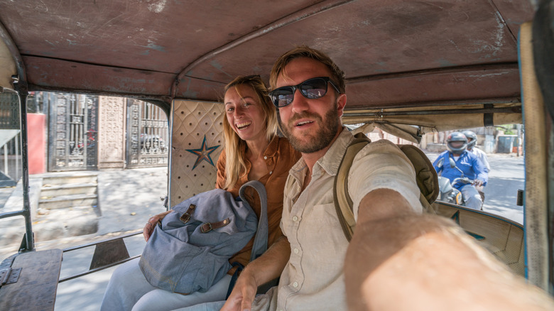 Travel couple taking selfie in rickshaw