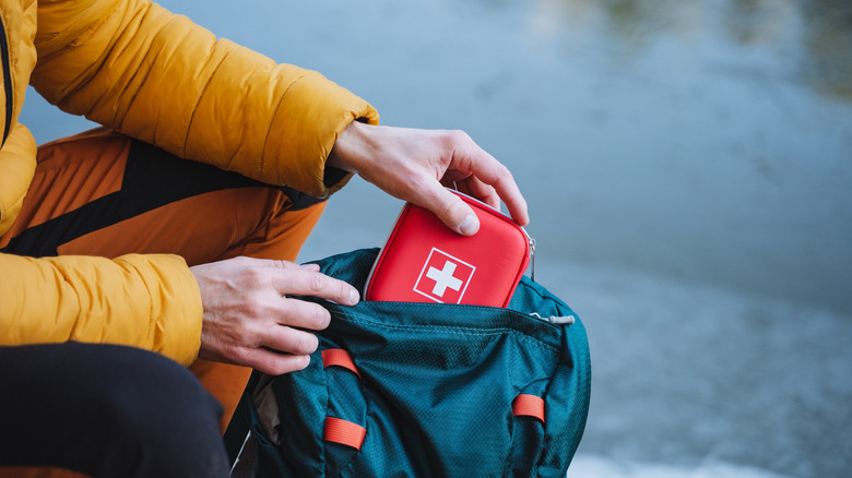 Hiker adding first aid kit to hiking backpack